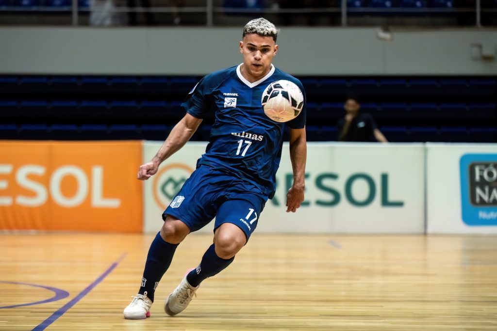 Atleta do Minas, de camisa azul com o número 17, conduz a bola em quadra, em jogo da LNF Cresol