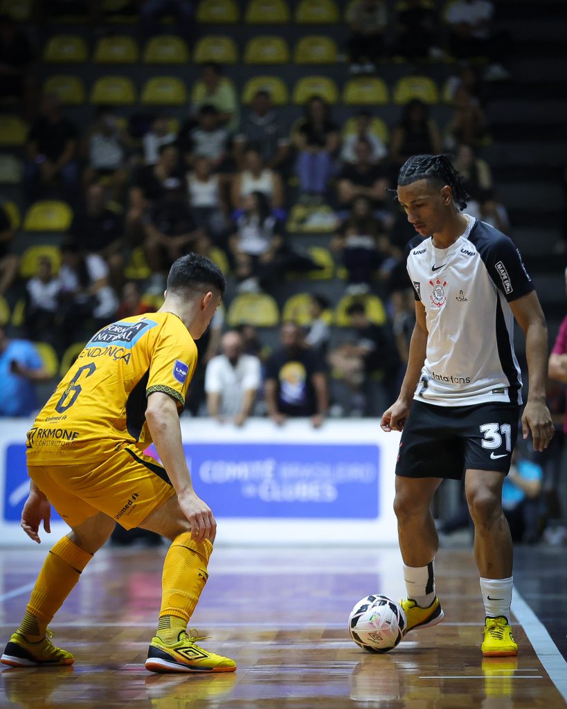 Atleta do Corinthians, de camisa branca, protege a bola diante de um marcador do Magnus, de uniforme amarelo, na ida das quartas de final da LNF Cresol